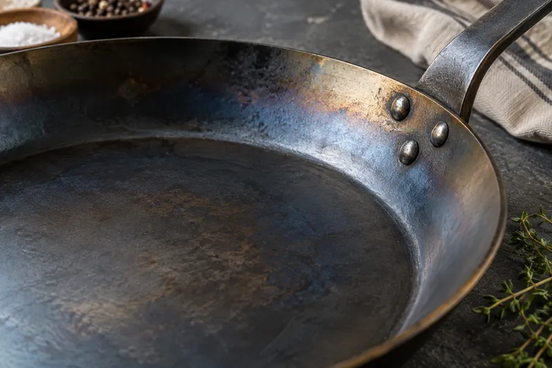 Blue and bronze patina across a carbon steel pan